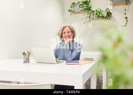 Senior as a competent manager at the laptop computer in the coworking office Stock Photo
