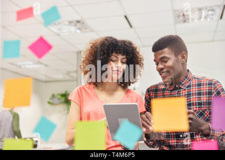 Two young freelancers as software developer team with tablet computer in start-up office Stock Photo