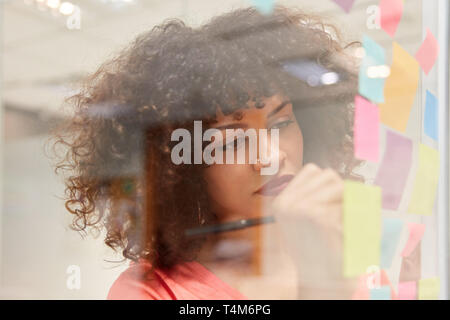 Young business woman writes ideas on sticky notes in creative brainstorming workshop Stock Photo