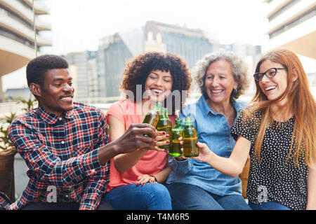 Group of friends toasting with beer on the house roof after work Stock Photo