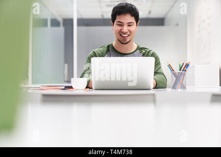 Smiling young man as a computer science student or software developer at the computer Stock Photo