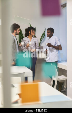 Team members drink a cup of coffee in a small talk break in the office or seminar Stock Photo