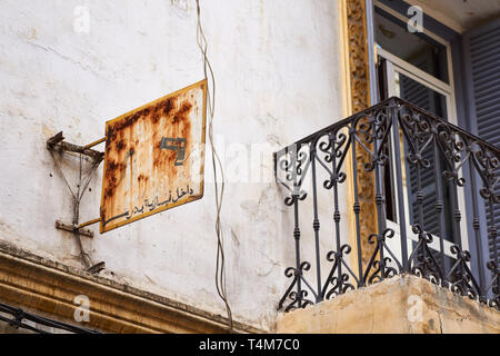 Rusty old hairdresser shop sign in Arabic writing and a balcony in Tangier, Morocco Stock Photo