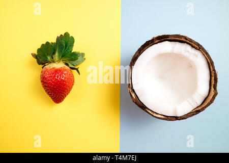 Coconuts and strawberry on blue and yellow background. Flat lay, top view Stock Photo