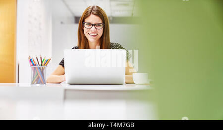 Young Businesswoman With Laptop Computer Works In Co-Working Space Stock Photo