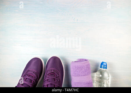 Sport shoes, bottle of water and towel on blue wooden background. Sport equipment. Concept healthy lifestyle, sport and diet. Top view, copy space Stock Photo