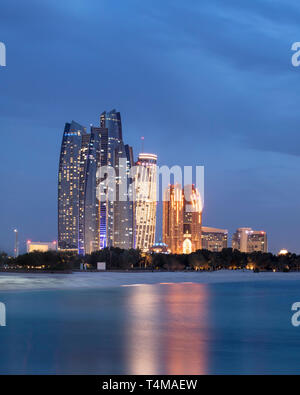 ABU DHABI, UNITED ARAB EMIRATES - April 5, 2019: Etihad Towers (left), which consist of residential apartments and a Jumeirah hotel, in Abu Dhabi.  (  Stock Photo