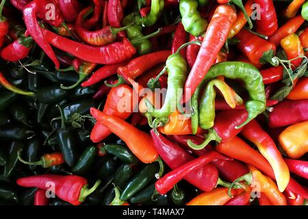 Mixed color of chili, widely used in many cuisines as a spice to add heat to dishes, on a surface of a bucket in a market, top view. Stock Photo