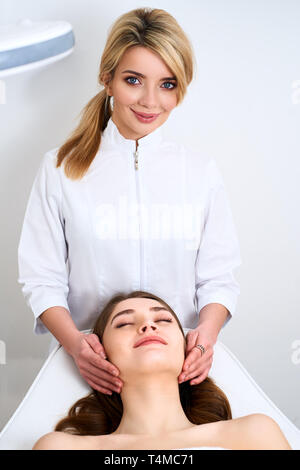 Beautician cleaning woman's face. Spa skincare treatment. Cosmetologist with patient on medical chair. Healthy skin cosmetology. Masseur making relax Stock Photo