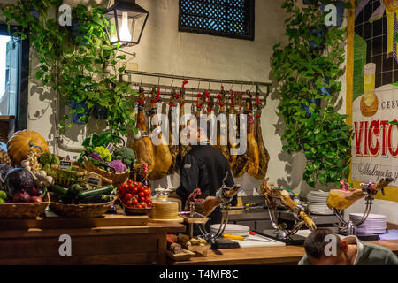 Malaga, Spain 04.04.2019: man waiter butcher in el pimpi restaurant in Malaga who cuts a slices of traditionally spanish jamon de bellota ham Stock Photo