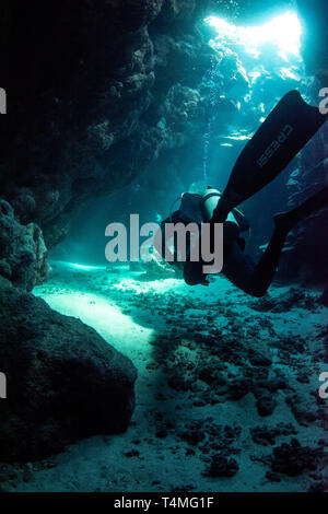 Underwater photograph of a scuba diver with Cressi fins swimming through a cave in the red sea, Egypt. Stock Photo