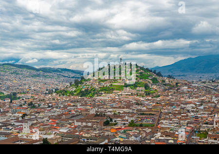 The historic city center of Quito in the Andes mountain range with the Panecillo hill and Virgin of Quito and a dramatic cloudy sky, Ecuador. Stock Photo
