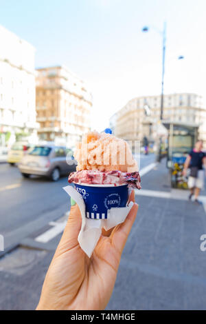 Female hand holding Italian ice cream with italian street as a background Stock Photo