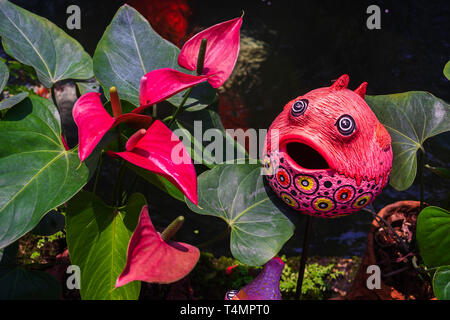 Cute colorful fish statue and Red anthurium flowes ( tailflower, flamingo flower, laceleaf ) decoration in the garden Stock Photo