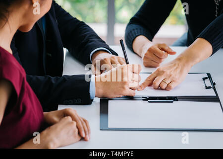 Close-up of married couple signing papers alongside with other witness or agent - can be divorce, law, liability, evidence agreement for marriage Stock Photo