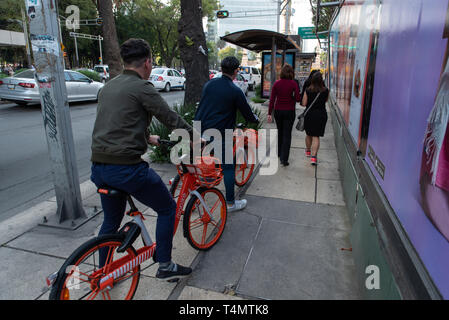 2 men use Mobike, a Chinese bike sharing app, in Mexico City. Stock Photo