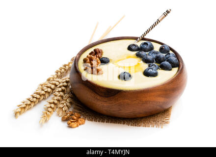 Wooden  bowl of semolina porridge with blueberry and walnut isolated on white Stock Photo