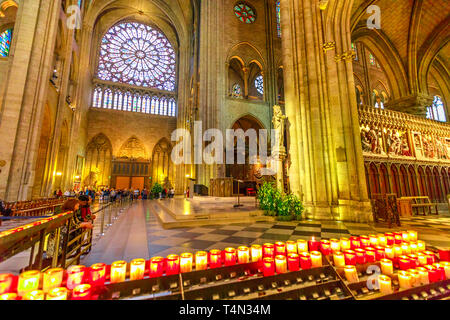 PARIS, FRANCE - JULY 1, 2017: People lighting the candles in central nave altar of Notre Dame of Paris gothic cathedral. Stained glass rose windows on Stock Photo