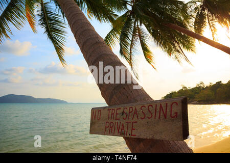 No trespassing sign on tropical palm tree at beach Stock Photo