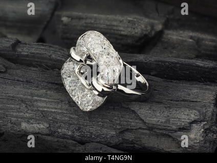 Golden Jewelry ring with diamonds, on black coal as background Stock Photo