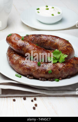 Traditional homemade coiled sausage with spices and sour cream on wooden table Stock Photo