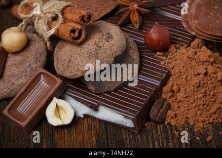 Chocolate assorment with cocoa powder, nuts, coffee and spices on wooden table Stock Photo