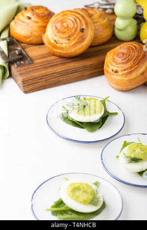 Deviled eggs with avocado and spinach and roll buns on festive Easter table, close up, selective focus Stock Photo