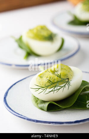 Deviled eggs with avocado and spinach on festive Easter table, close up, selective focus Stock Photo