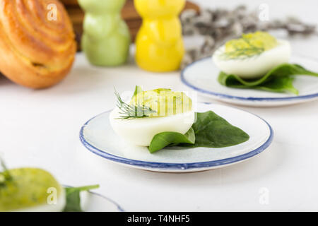 Deviled eggs with avocado and spinach and roll buns on festive Easter table, close up, selective focus Stock Photo