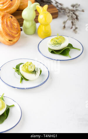 Deviled eggs with avocado and spinach and roll buns on festive Easter table, close up, selective focus Stock Photo