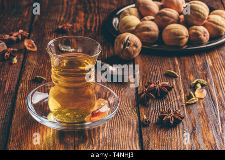 Oriental tea with star anise, cardamom and dried lime in armudu glass over wooden surface Stock Photo