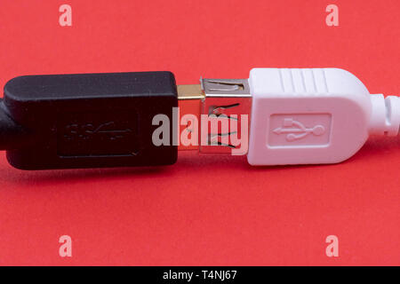 data cable extension plug white and black cable together on red background Stock Photo