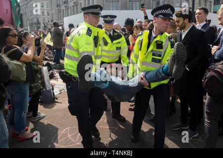 An activist with Extinction Rebellion is arrested during the London protest about climate change in a blocked-off Oxford Circus , on 17th April 2019, in London, England.