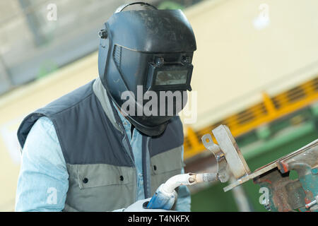 male in face mask welds with argon-arc welding Stock Photo