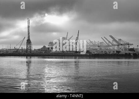 Black And White Photo Of The Sun Rising Over The Los Angeles Container Terminal And Terminal Island, California, USA. Stock Photo