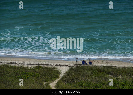 Hutchinson Island, FL/United States - 03/12/19: Couple sitting at the beach in chairs watching the waves on a peaceful day. Stock Photo