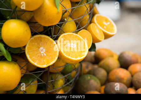 Tropical oranges hanging out and in basket. Focus on half cut orange Stock Photo