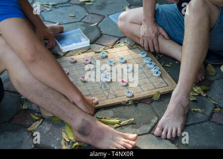 Closeup two old men playing Chinese chess on Hanoi sidewalk, Vietnam. Focus on chessboard Stock Photo