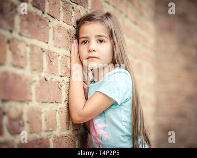 Girl, 5 years old, leaning against a wall, portrait, Germany Stock Photo