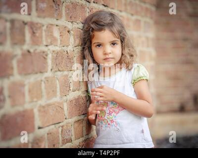 Girl, 3 years old, leaning against a wall, portrait, Germany Stock Photo