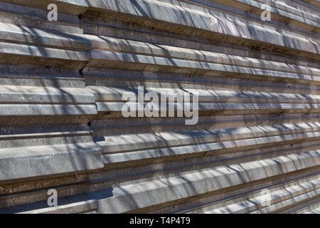 Fragment of an old fence of an abandoned construction site, made of metal sheets. Sunlit fragment of the fence. Metal corrugated sheet Stock Photo