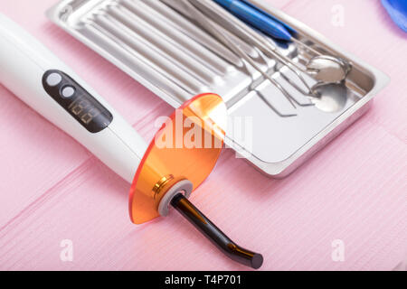 Close-up shot of dental curing light and sterilized dental instruments on metal tray ready to be used Stock Photo