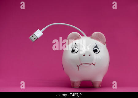 White porcelaine piggy bank with USB cable coming out of back on pink bacgdrop, sceptical look sideways. Stock Photo