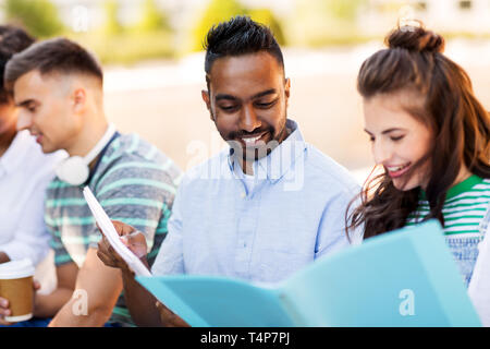 education, international and people concept - group of happy exchange students with notebooks outdoors Stock Photo