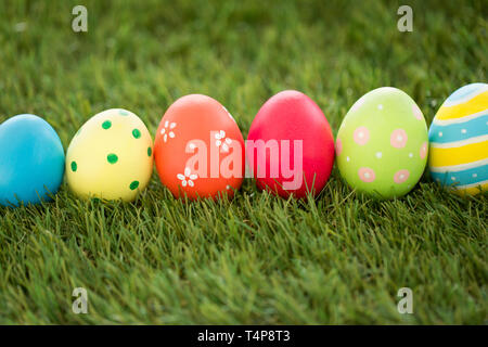 easter, holidays and tradition concept - row of colored eggs on artificial grass Stock Photo