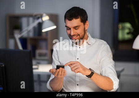 business, technology and internet of things concept - businessman using smart speaker working at night office Stock Photo