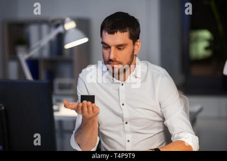 business, technology and internet of things concept - businessman using smart speaker at night office Stock Photo