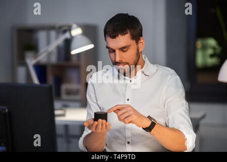 business, technology and internet of things concept - businessman using smart speaker working at night office Stock Photo