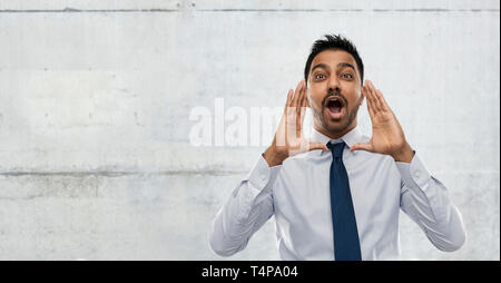 business, stress and people concept - indian businessman shouting or calling over gray concrete wall background Stock Photo