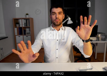 business, technology and people concept - businessman using gestures at night office Stock Photo